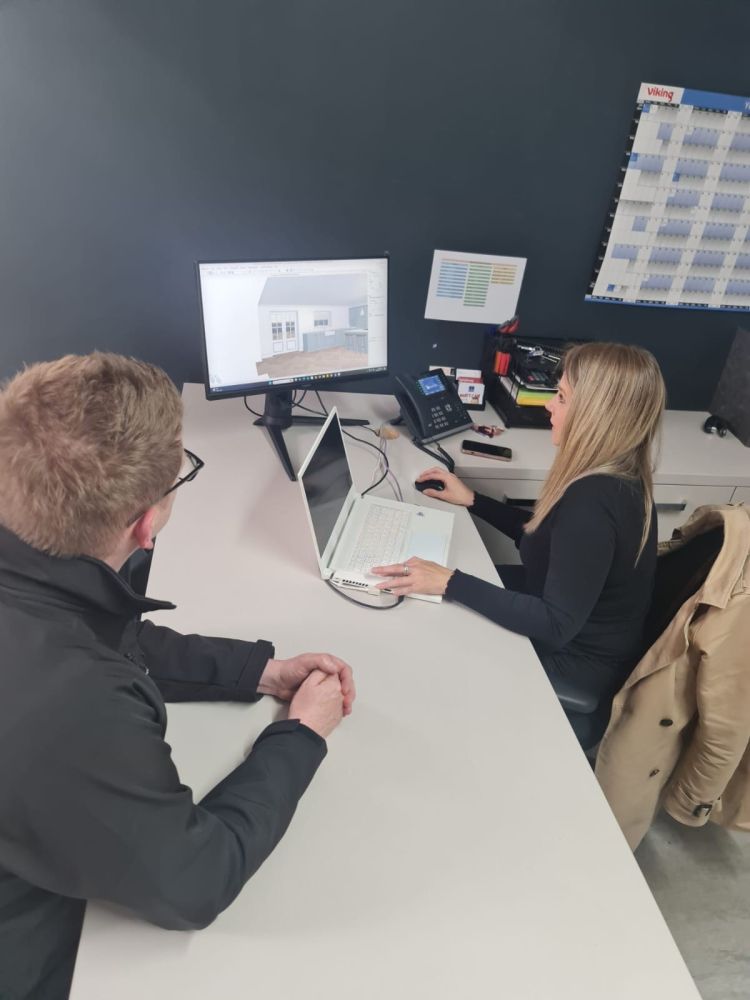 A man and woman sit at a desk, focused on a computer screen